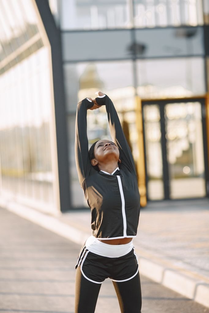 A vibrant woman stretches energetically outdoors, embracing healthy living and wellness.